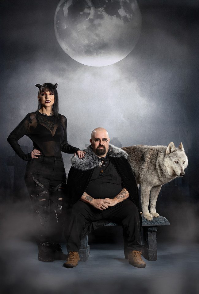 A mystical scene with a woman, a man, and a wolf under a full moon.